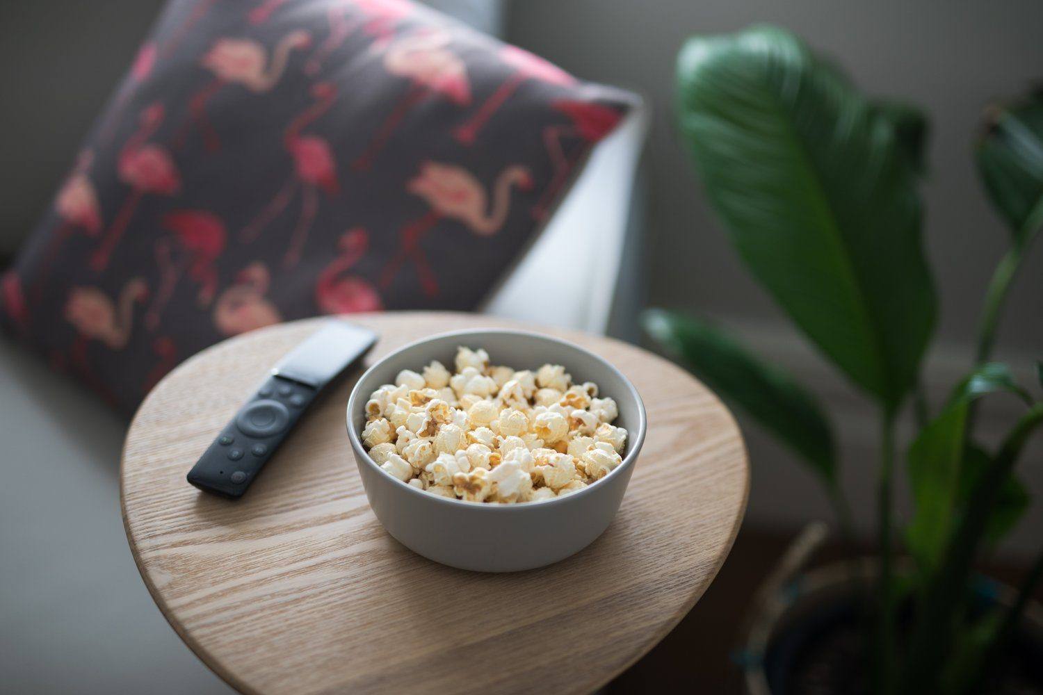 Miska popcornu i pilot na kanapie w przyciemnionym pokoju