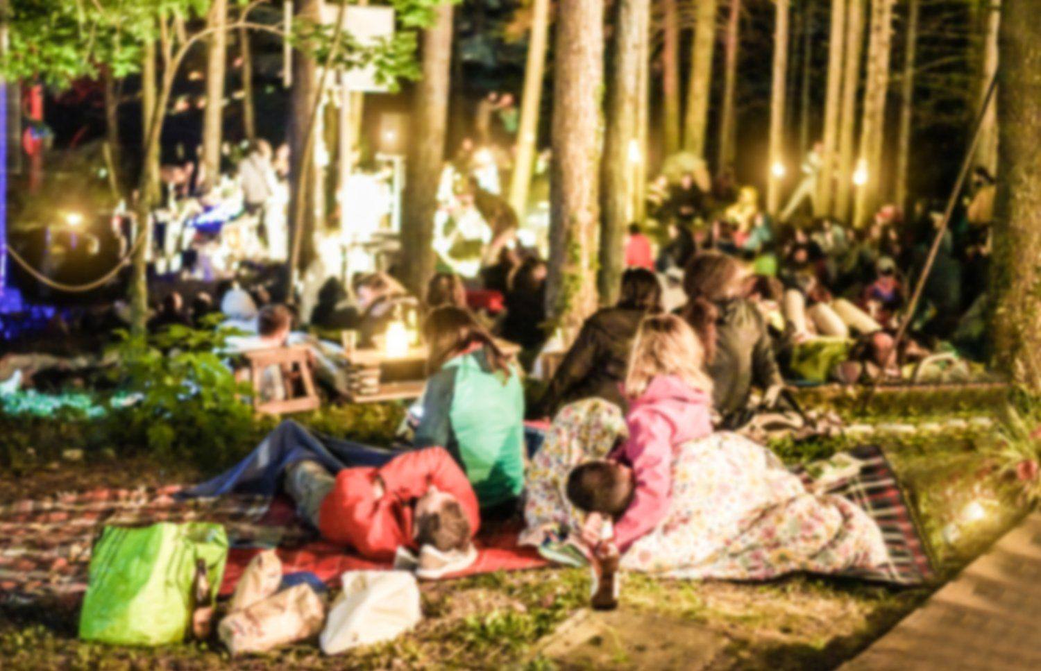 Ludzie na kocach oglądający film pod gołym niebem nocą